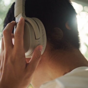 Asian young man wearing headphones while looking through the window.