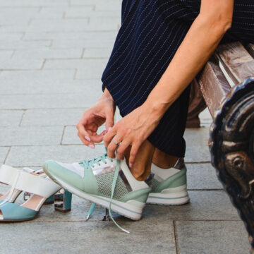 A woman takes off her shoes and wears sneakers for the comfort and health of her legs. Pain in the legs when walking around the city in shoes with heels.