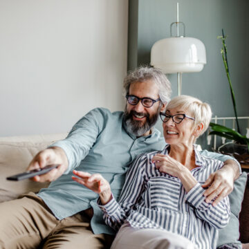 Senior couple sitting in a living room at home and watching TV